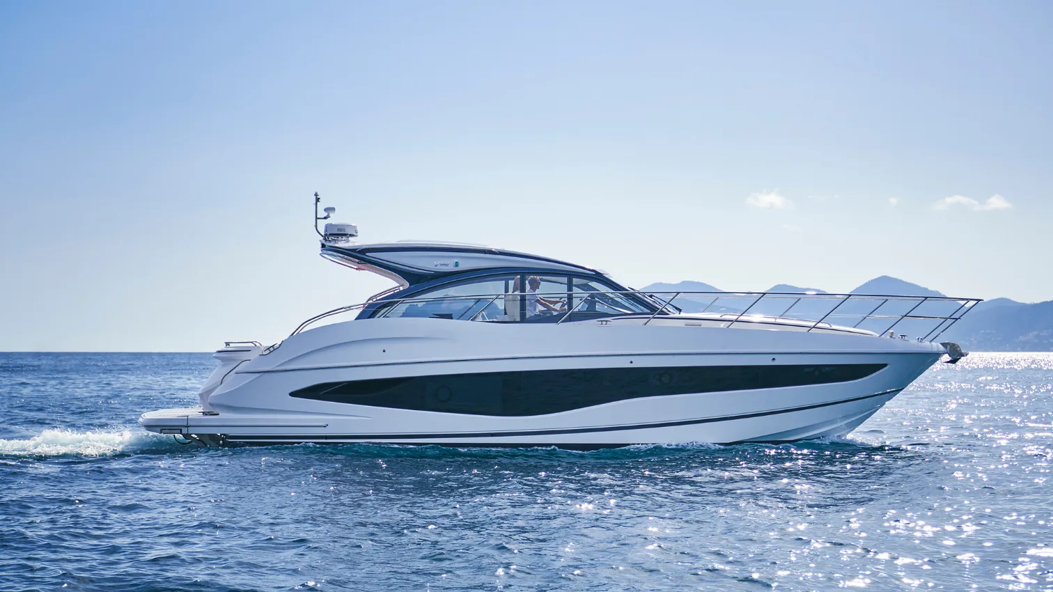 Princess V50 Sport yacht cruising on calm water with its sunroof open and the helm visible from the side.