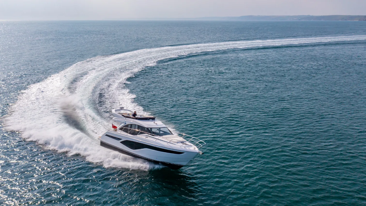 Princess F50 flybridge yacht running and turning at speed, seen from above with a curving white wake.