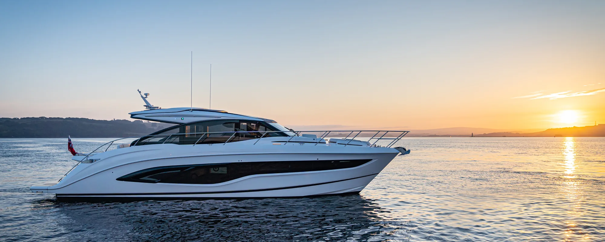 Princess Sport yacht cruising at sunset on calm water, full profile view with warm light along the hull.