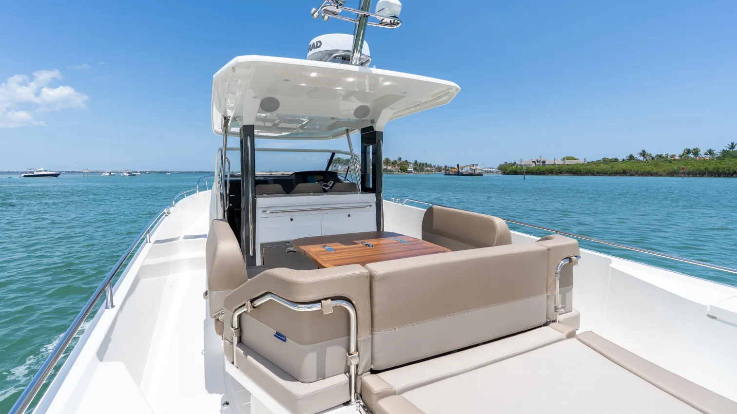 Nimbus T11 cockpit and aft entertaining area with a teak table and wraparound lounge seating.